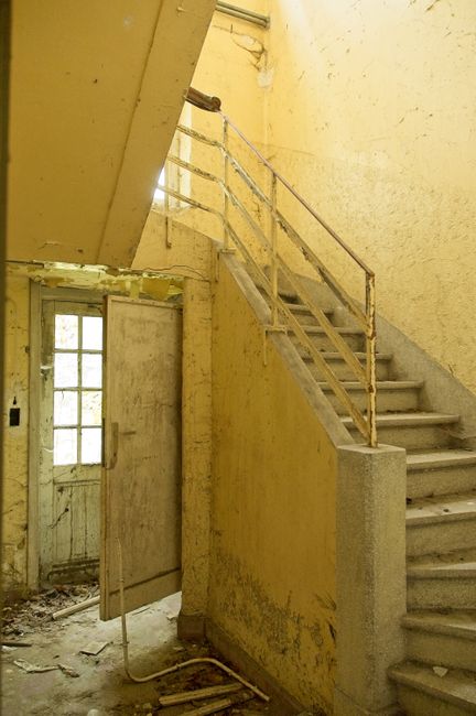 A close-up view of a weathered concrete staircase outdoors, with six visible steps featuring chipped edges, cracks, and signs of wear. The steps are painted in a faded blue-gray color, with some areas